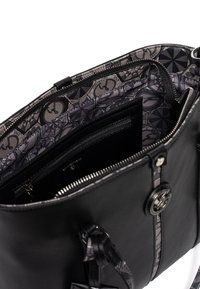 Czarna skórzana torebka o gładkiej fakturze, z wzorzystym szarym wnętrzem, zamykanymi na suwak kieszeniami oraz metalowymi akcentami.