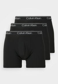 Drie paren zwarte boxershorts met een aansluitend ontwerp. Elk paar heeft een wit "Calvin Klein"-logo op de elastische tailleband.