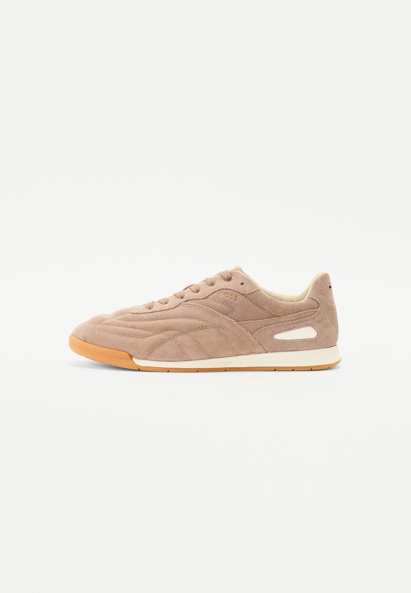 Beige suede streidsneaker, millel on reljeefne pind, koonus valge vahesolek ja pruun kummist välisolek. Kaasa tuleb paelad ja küljeaktsendid.
