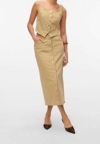 Conjunto de dos piezas en color beige que incluye un top cropped sin mangas con botones y una falda a la rodilla a juego con un cierre de botones en la parte delantera.