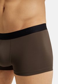 Shorts boxer marroni con una cintura elastica nera con nome della marca in rilievo. Tessuto liscio con una vestibilità aderente e cuciture minime.