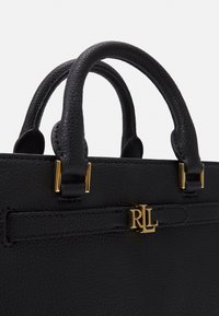 Sac à main en cuir noir avec une texture en relief, deux poignées courtes, accents en métal doré et un logo en relief à l'avant.