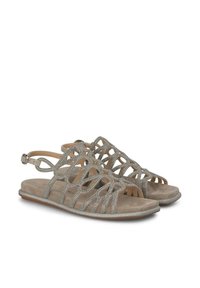 Płaskie sandały z metaliczno-szarym zamszowym wierzchem, z dekoracyjnymi wycięciami i błyszczącymi akcentami, regulowanym paskiem wokół kostki oraz płaską podeszwą.