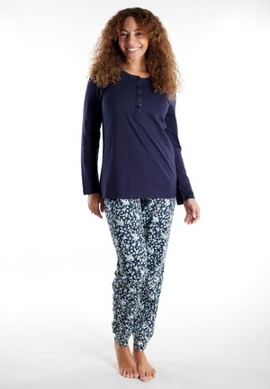 Navy long-sleeve top with buttoned henley neck paired with floral-patterned pants in shades of blue, white, and green. Soft, casual fabric.