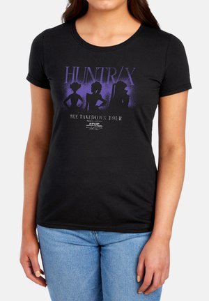 Black fitted t-shirt with purple silhouettes of three characters, text "HUNTR/X The Takedown Tour" and small K-pop Demonhunters logo below.