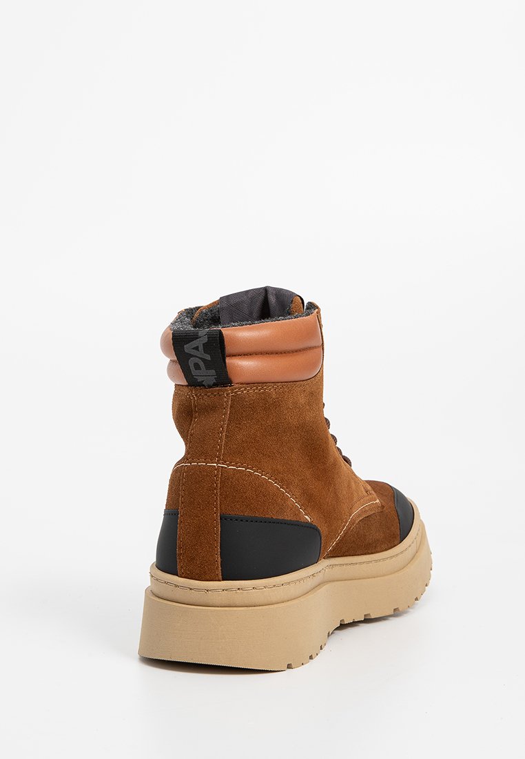 Braune Wildleder-Boots bis Knöchelhöhe mit Lederdetails, gepolstertem Schaft, robustem Gummisohle und kontrastierendem schwarzen Panel an der Seite.