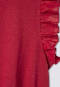 Top rosso caratterizzato da una texture morbida con un'accademia arricciata su un lato. Il tessuto appare leggero con una finitura liscia.