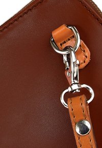 Braune Lederbörse mit strukturiertem Oberflächen, ausgestattet mit einem metallischen Schnapphaken und einem orangefarbenen Ledertrageband. Sichtbare Nähte und Hardware-Details.