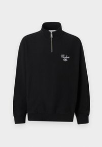 Μαύρο φούτερ με φερμουάρ μέχρι το μέσο με ψηλό γιακά, ριμπ μανσέτες και τελείωμα, με λευκό λογότυπο "Carhartt Wip" σε γραφή στο αριστερό μέρος του στήθους.