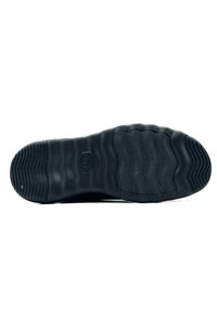 Suela de zapato de goma negra con textura acanalada y patrones ondulados. Presenta un logo en el centro. Material suave y duradero.