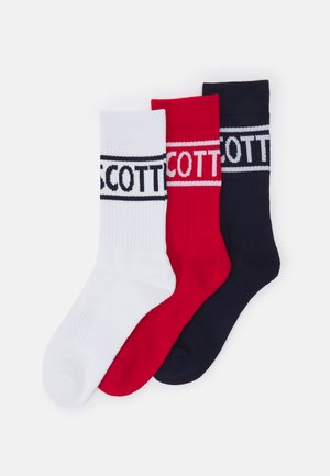 Trzy pary skarpetek roboczych w kolorach białym, czerwonym i granatowym, każda z wyraźnymi poziomymi paskami i częściowo widocznym tekstem marki blisko góry.