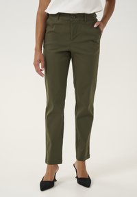 Olive zelene hlače iz bombažne mešanice s slim fit krojem, ki vključujejo sprednje gumbne zapore, stranske žepe in obliko hlačnic, ki se zožujejo. Črne elegance s koničastimi petami.