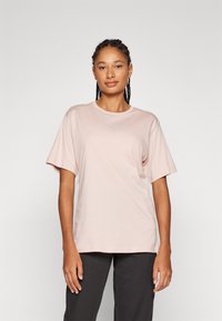 Lyserød bomulds t-shirt med korte ærmer, rund halsudskæring og lille hvidt logo på brystet. Casual pasform, blød tekstur, minimalistisk design.