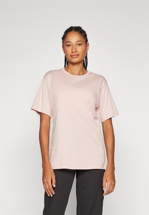 Camiseta de algodón rosa claro con mangas cortas, escote redondo y pequeño logo blanco en el pecho. Corte casual, textura suave, diseño minimalista.