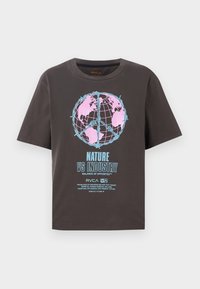 Mørkegrå t-shirt med korte ærmer, prydet med et farverigt globusdesign i pink og blå, samt teksten "NATURE VS INDUSTRY" i fed skrift.