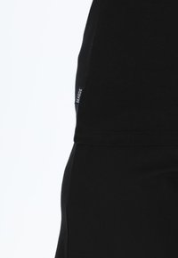 Sort bomulds T-shirt med lige snit, der har et lille sideklistremærke med "SEASIDE" label, glat tekstur og minimalistisk design.