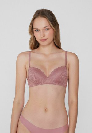 Lace bralette in zachte mauve met verstelbare bandjes, geschulpte randen en een textuur met bloempatroon. Bijpassende slip in een vergelijkbare tint.