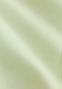 Tessuto giallo chiaro con trama fine intrecciata, mostrato in un primo piano con morbide pieghe e superficie liscia.