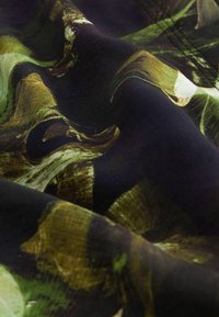 Tissu à fond sombre avec un design abstrait vert vif et marron, présentant une texture lisse et des motifs ondulés.