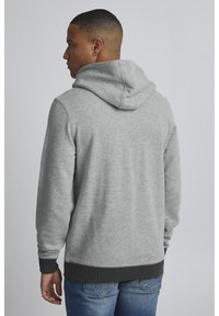 Gray hoodie with a large hood, ribbed cuffs, and hem. Soft texture with a relaxed fit, shown worn from the back with blue jeans.