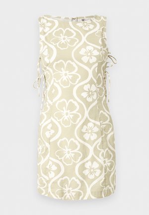 Robe sans manches beige avec des motifs floraux blancs et des vagues, attaches latérales et un col rond, présentée sur un fond uni.