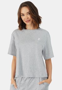 Grijze katoenen t-shirt met een ronde hals en korte mouwen. Bevat het DKNY-logo in het wit op de linkerborst. Zachte textuur, relaxte pasvorm.