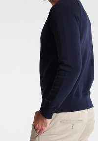 Felpa girocollo blu navy realizzata in tessuto morbido, con polsini e orlo a costine, design aderente e texture liscia.