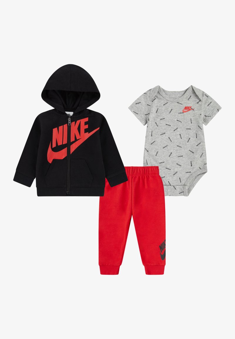 Nike dječja odjeća: crna zip-up hoodie s crvenim logotipom, sivi kombinezon s uzorkom, i crvene trenirke s logotipom na gležnju.