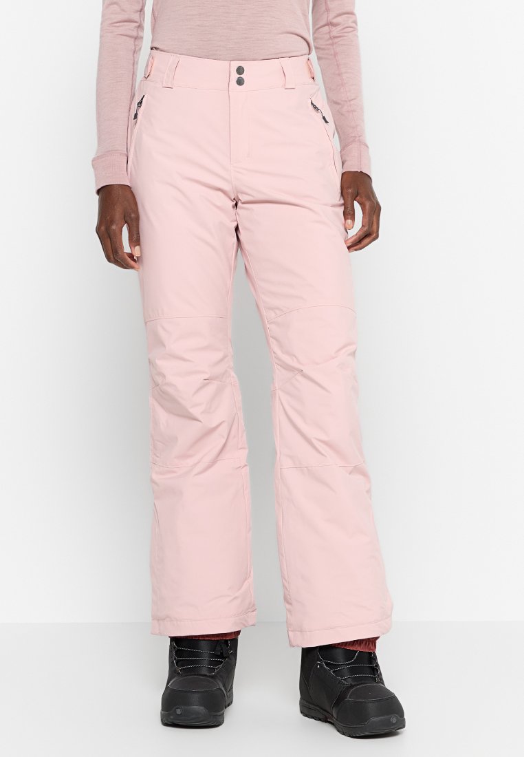 Jasnoróżowe spodnie śniegowe o gładkiej fakturze, z dwiema kieszeniami, zamkiem błyskawicznym i luźnym krojem, w komplecie z czarnymi butami śniegowymi.