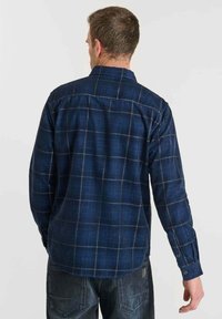 Blauw geruite flanellen shirt met een button-down kraag, lange mouwen en een relaxte pasvorm. Bevat oranje en grijze rasterpatronen verspreid over het shirt.