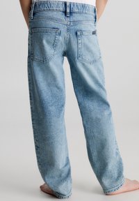 Vaqueros de mezclilla azul claro con un corte relajado, que cuentan con dos bolsillos traseros y una textura ligeramente desgastada. La cintura tiene un diseño fruncido.