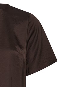 Gros plan d'une chemise en tissu soyeux marron chocolat à manches courtes mettant en valeur la texture lisse et les détails des coutures à l'épaule et à la manche.