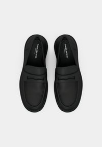 Fekete bőr loaferek sima felülettel, a vádlin átívelő pánttal és masnival. Slip-on kialakítás kerek orral.