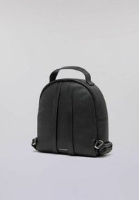 Schwarzer Lederkompakt-Rucksack mit Obergriff, zwei senkrechten genähten Streifen und verstellbaren Seitenriemen, vor einem schlichten hellen Hintergrund.