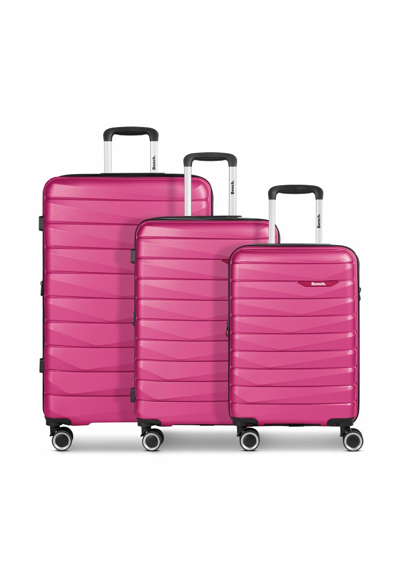 Drie roze harde koffers met horizontale golfpatronen, zilveren telescopische handgrepen en elk vier wielen voor gemakkelijke mobiliteit.