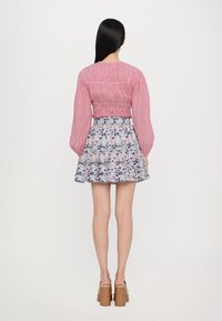 Rød- og hvitstripete smokkertopp paret med en floraltrykt volangskjørt. Modellen har på seg brune blokkhelede sko.