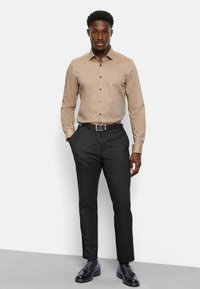 Beige button-up shirt with subtle texture, black tailored pants, and black shoes. Shirt has long sleeves and a classic collar.