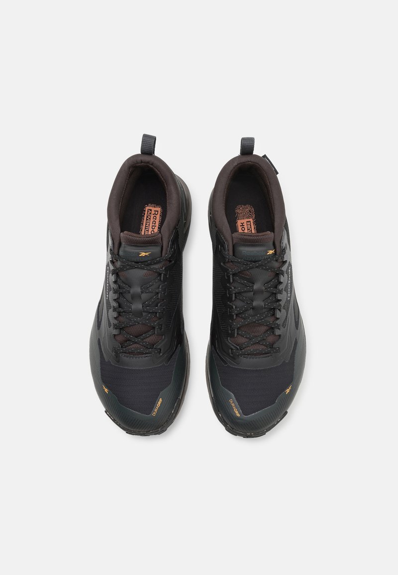 Scarpe da ginnastica nere con accenti marroni scuri, tomaia in rete e sintetico, punta texturizzata e suola in gomma resistente. Presenta lacci arrotondati.