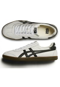 Sneakers in pelle bianca con accenti e strisce nere, suola in gomma, punta rotonda e design con lacci. Stile atletico classico con dettagli testurizzati.