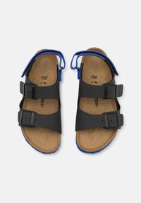 Sandal nera con due cinghie regolabili e chiusura a fibbia, caratterizzata da un accento blu lungo la soletta e una soletta testurizzata.