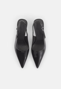 Escarpins slingback noirs à bout pointu avec brides à boucle réglables et texture cuir lisse, vus de dessus sur fond blanc.