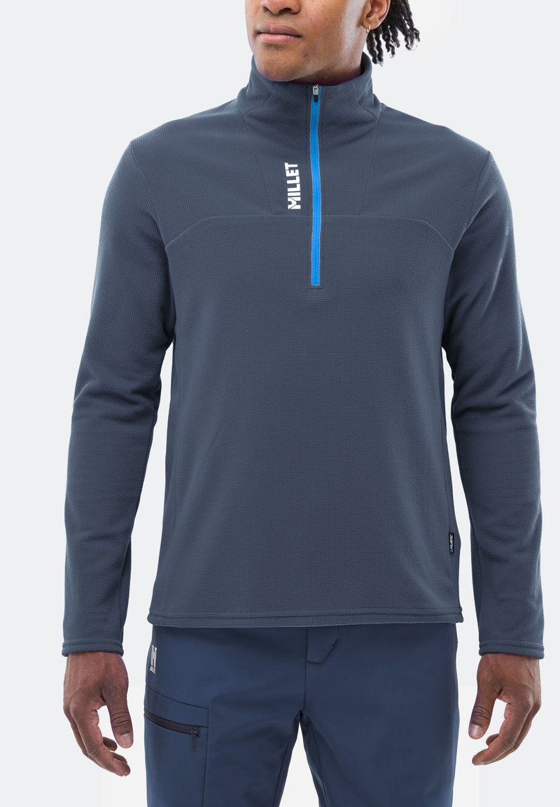 Pull en fleece bleu avec demi-zip et col haut ; présente un tissu texturé, une fermeture éclair bleue contrastante et un logo de la marque sur la poitrine.