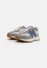 Scarpe da ginnastica grigio e bianche con accenti blu, caratterizzate da una parte superiore liscia, suede testurizzato e una suola in gomma con battistrada circolare.