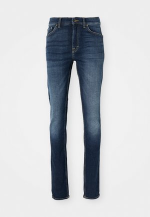 Vaqueros de mezclilla azul oscura con corte ajustado, que cuentan con cinco bolsillos, costuras doradas y un frente ligeramente desgastado para un look casual.