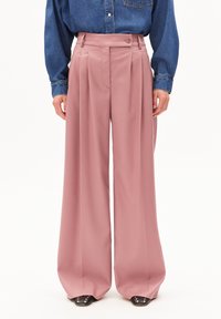 Lichtroze wijde broek met een hoge taille, voorzien van plooien, een knoopsluiting, en gecombineerd met een denim shirt en zwarte puntige schoenen.