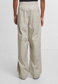 Light beige wide-leg trousers with an elastic waistband. Features two back pockets and a smooth, slightly textured fabric.