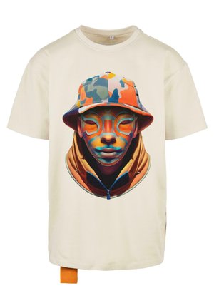 Krémové tričko s živým grafickým potiskem obličeje v barevném klobouku s kšiltem a oranžové mikině na zip.