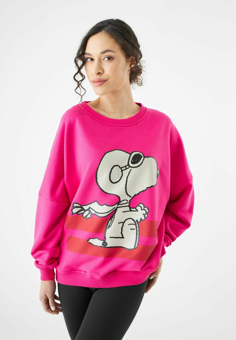 Helles pinkes Sweatshirt mit einem Grafikumdruck von Snoopy, mit weißen und schwarzen Akzenten, lässiger Passform, gerippten Bündchen und horizontalen Streifen darunter.