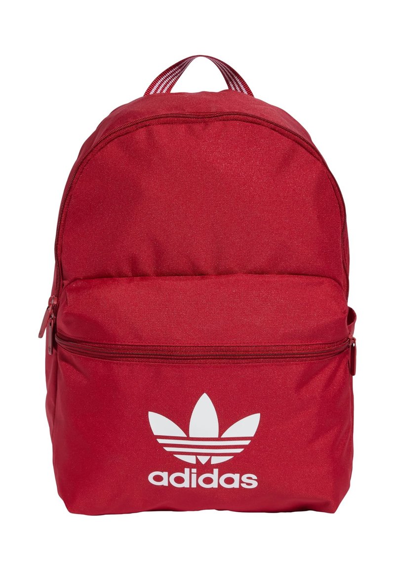 Mochila de tela roja con forma redondeada, bolsillo frontal con cremallera y destacado logo de Adidas en blanco en la parte frontal inferior. Tirantes de rayas verticales.