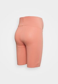 Calções de bicicleta cor-de-pêssego feitos de um material elástico, apresentando uma cintura alta e um acabamento suave, sem padrões visíveis ou elementos de hardware.